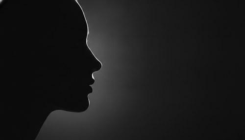 Black and white editorial side-profile silhouette emphasizing the nose line, illustrating rhinoplasty cost commentary by Frank Agullo, MD, FACS.
