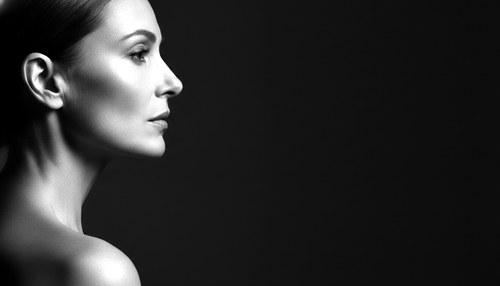 Black and white profile portrait of a woman in her fifties, jawline and neck lit as a single architectural line.